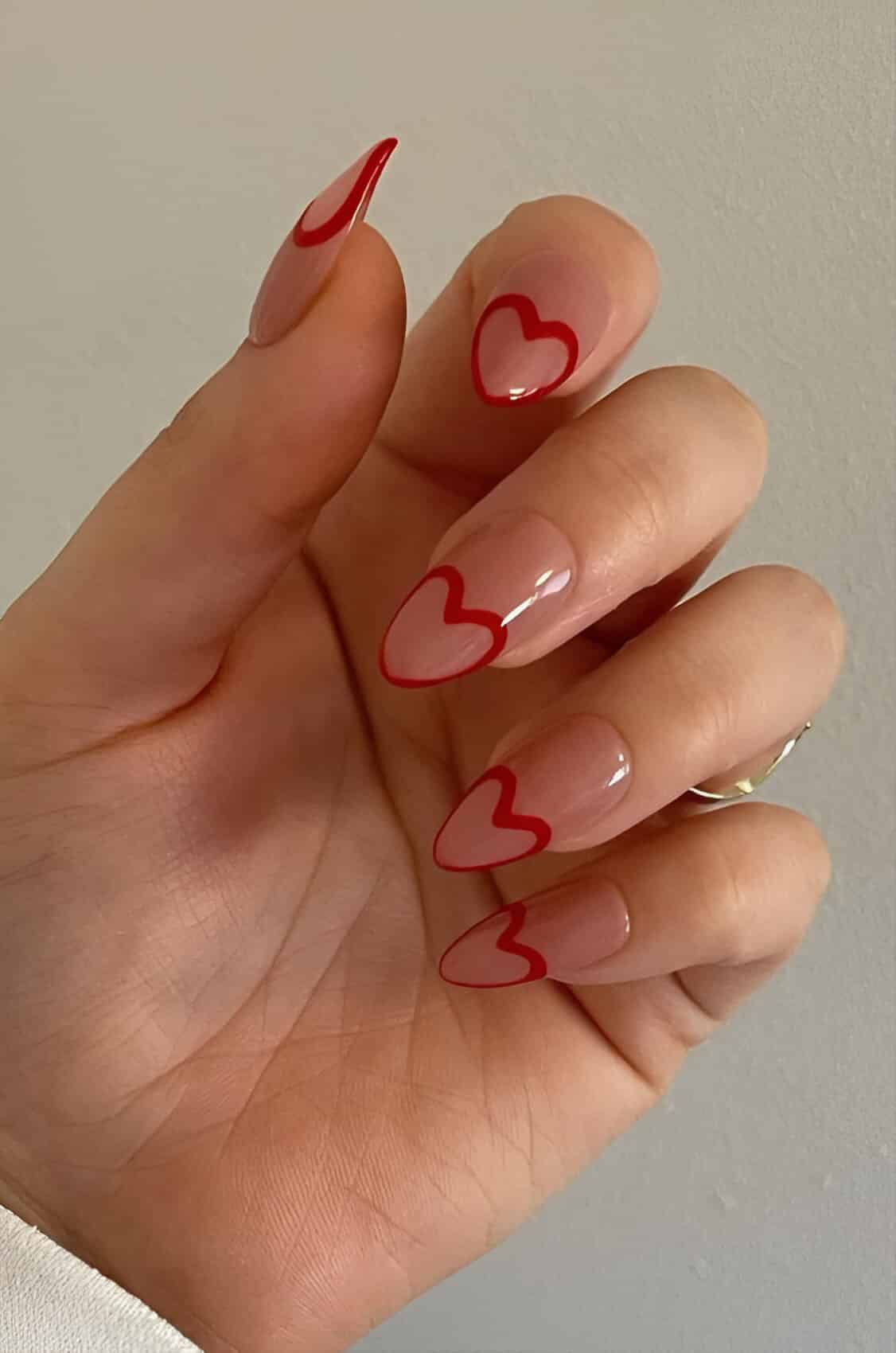 Red Valentine’s Day acrylic nails with white heart details and glitter accents