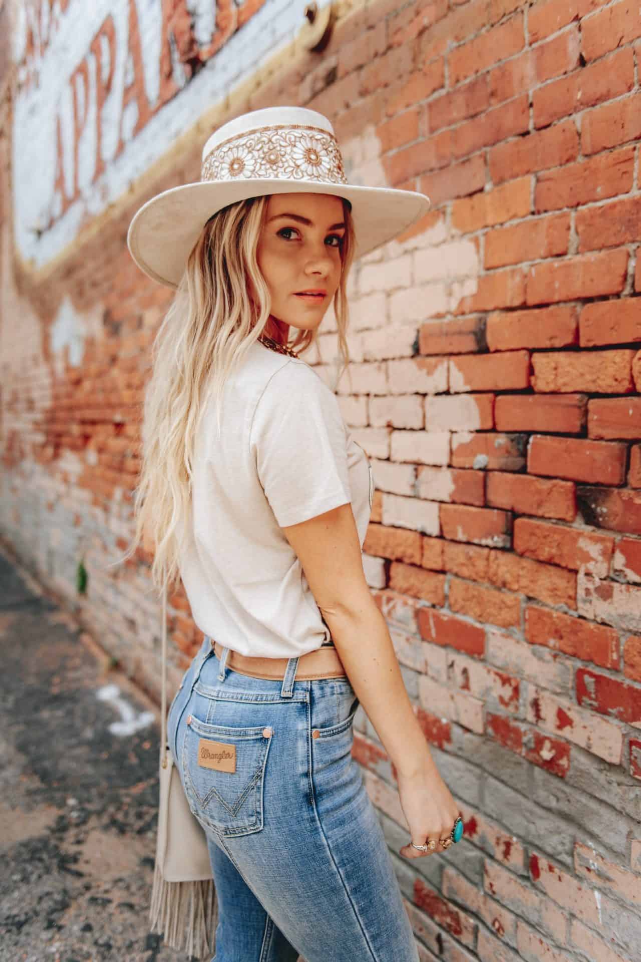 Woman in a suede jacket, hat, and tall leather boots